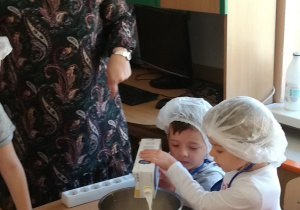 Dzieci wlewają z kartonu do garnka mleko