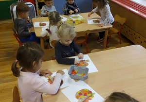 dzieci przy stoliku wykonują prace plastyczną - sylwetkę jeżyka