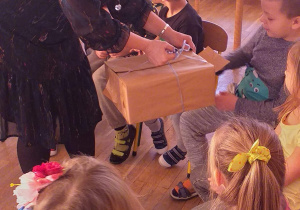 Dzieci losują kolorowe kulki z pudełka trzymanego przez wróżkę