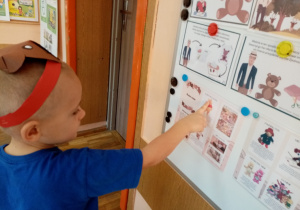 Chłopiec wskazuje na tablicy ilustrację przedstawiającą historię misia.