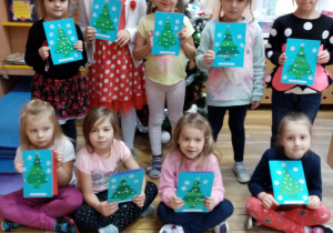 Dziewczynki z grupy V prezentują wykonane przez siebie kartki świąteczne.