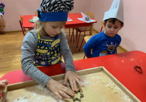 Dzieci z gr 4 integracyjnej wyciskają foremkami ciasto na pierniki