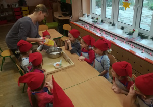 Dzieci obserwują jak pani robi ciasto na pierniki.