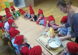 Dzieci obserwują jak pani robi ciasto na pierniki.