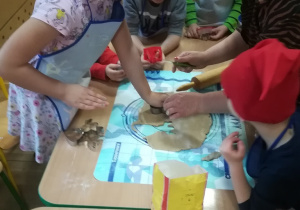 Dzieci wykrawają pierniki z rozwałkowanego ciasta