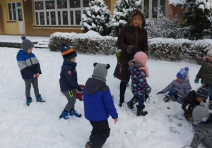 Dzieci z grupy 1 i 2 z panią Beatką bawią się na śniegowym placu zabaw