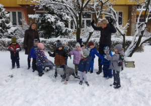 Dzieci z grupy 1 i 2 z panią Beatką i Ewą pozują do pamiątkowego zdjęcia na śniegowym placu zabaw