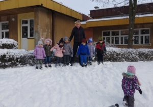 Dzieci z gr 1 z panią Ewą pozują do pamiątkowego zdjęcia na górce śniegowej