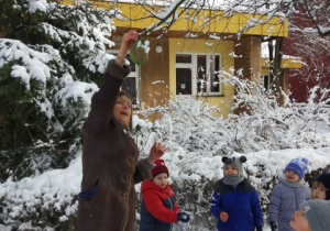 Pani Beatka z dziećmi z gr 2 strzepuje śnieg z drzewka
