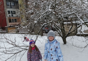 Dziewczynki radośnie pozują do pamiątkowego zdjęcia na zimowym ogrodzie przedszkolnym