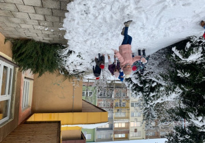 Dzieci bawią się śniegiem i lepią bałwana