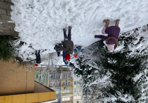 Dzieci bawią się śniegiem i lepią bałwana