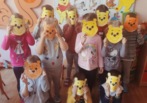 Dzieci z grupy 3 pozują do zdjęcia z maskami Kubusia Puchatka