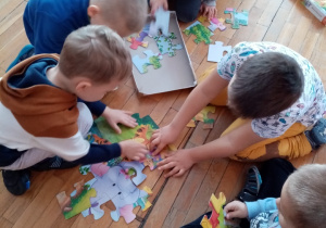 Dzieci układają puzzle z Kubusiem Puchatkiem.