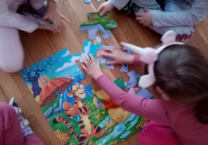 Dzieci układają puzzle z Kubusiem Puchatkiem.