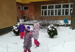 Dzieci spacerują po zaśnieżonym ogrodzie