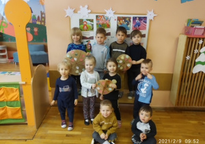 Dzieci z gr 1 pozują do pamiątkowego zdjęcia z własnoręcznie wykonanymi pracami plastycznymi związanymi z tematyką święta pizzy
