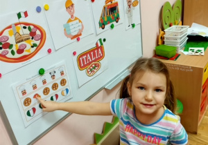 Dziewczynka z gr 3 rozwiązuje łamigłówki związane ze świętem pizzy