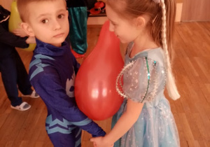 Dzieci w karnawałowych przebraniach - Kot i Elsa w zabawie z balonem