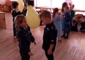 Dzieci w karnawałowych przebraniach - Policjantka i Policjant w zabawie z balonem