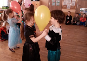 Dzieci w karnawałowych przebraniach - Czarodziejka i Kot w butach w zabawie z balonem
