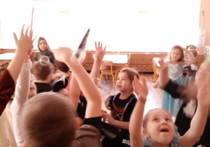 Dzieci w karnawałowych przebraniach tańczą i łapią bańki mydlane