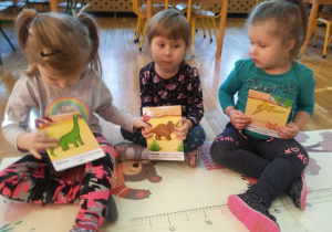 Dziewczynki z gr. II pokazują obrazki różnych dinozaurów.