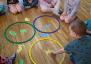 Dzieci tworzą zbiory dinozaurów według kolorów: żółte, niebieskie, zielone.