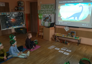 Dzieci na tablicy multimedialnej oglądają film o dinozaurach