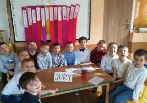 Chłopcy siedzą przy stoliku na którym jest napis JURY