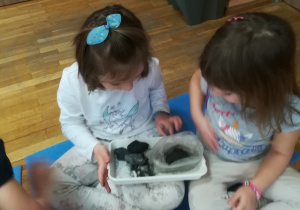 Dziewczynki oglądają bryłki węgla.