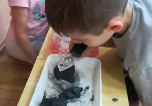 Dzieci oglądają przez lupy sól i węgiel