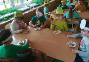 Dzieci siedzą przy stoliku i jedzą tort