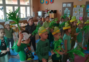 Dzieci z zielonymi miotełkami w ręku uczą się układu tanecznego