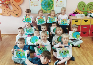 Dzieci pozują do pamiątkowego zdjęcia z pokolorowanymi rysunkami