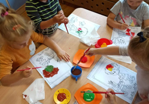 Dzieci kolorują farbami postacie dzieci przedszkolnych