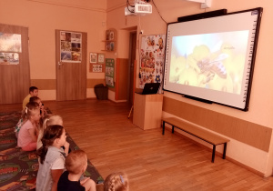 Przedszkolaki oglądają film edukacyjny o pszczołach.