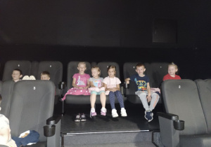 Dzieci siedzą na fotelach kinowych oczekując na bajkę