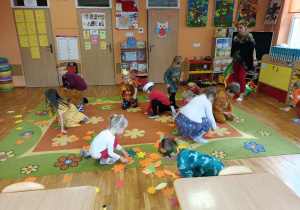 Zbieranie papierowych liści z podłogi przez dzieci