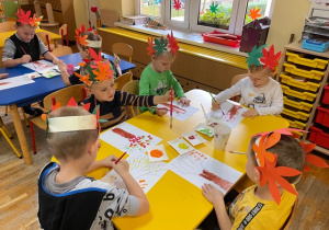 Dzieci wykonują prace plastyczne związane z tematyką jesienną