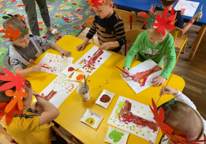 Dzieci wykonują prace plastyczne związane z tematyką jesienną