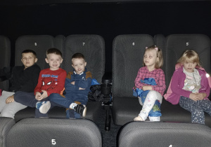 Dzieci siedzą na fotelach w kinie