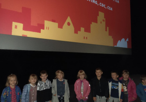 Dzieci stoją pod ekranem w kinie