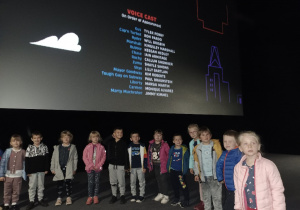 Dzieci stoją pod ekranem w kinie