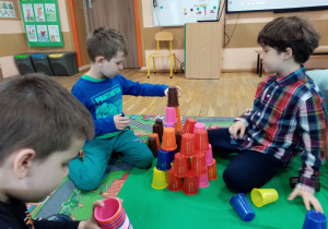 Chłopcy układają wieże z kolorowych kubeczków.