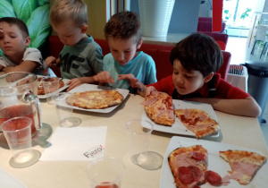 Chłopcy degustują zrobioną przez siebie pizzę.