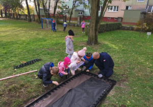 Pan Rafał z dziećmi buduje ścieżkę sensoryczną
