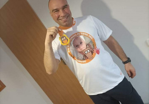 Pan Rafał pokazuje pamiątkowy medal z biegu charytatywnego "Dla Zosi"