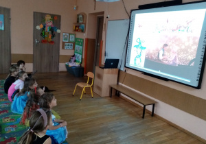Przedszkolaki oglądają prezentację multimedialną o postaciach z bajek.