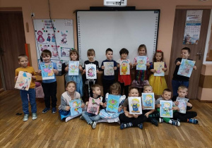Dzieci z gr 5 pozują do pamiątkowego zdjęcia z namalowanymi przez siebie rysunkami